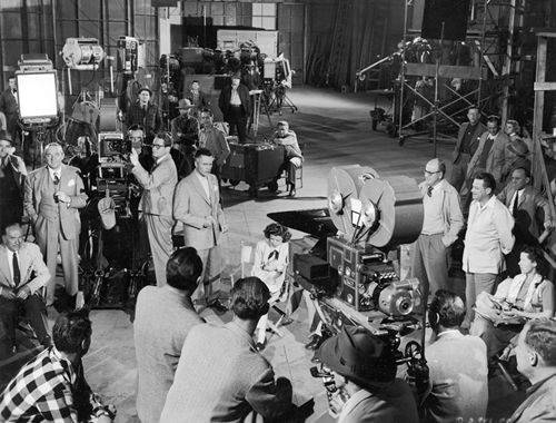 Tournage en studio avec caméra ancienne et nombreux techniciens
