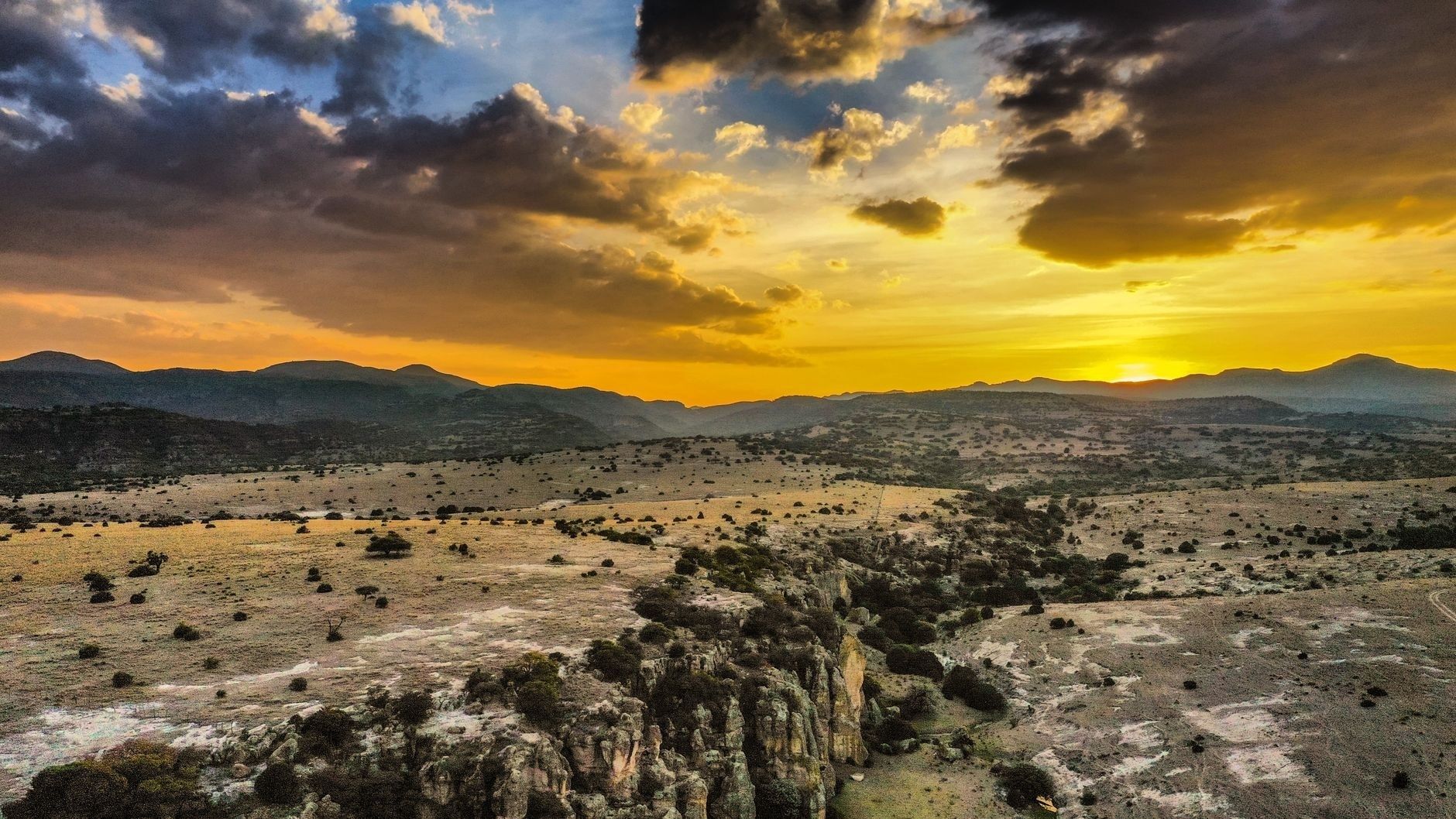 Paysage montagneux aride au coucher du soleil sous un ciel nuageux